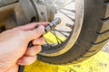 People hand are filling the tire pressure on the motorbike wheel from automatic air filler at filling station. Royalty Free Stock Photo