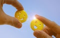 people hand holding yellow emoticon smiley face icon symbol on blue sky background