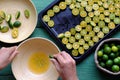 People hand squeeze juice out of kumquat fruits cut in half into bowl