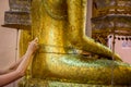 People hands cover to statue of Buddha with gold leaf in temple, Thai tradition Royalty Free Stock Photo