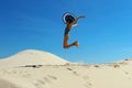 People, happiness, travel concept. Teenage girl wearing a big black hat jumping on a beach. Attractive girl jumping on the beach o Royalty Free Stock Photo