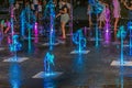 People have fun in the city square near Pedestrian Fountain illuminated in blue