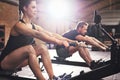 People having hard workout on rowing machines