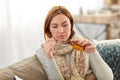 Sick woman in scarf pouring cough syrup at home Royalty Free Stock Photo