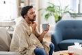Sick man with tea touching his sore throat at home Royalty Free Stock Photo