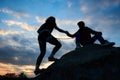 People helping each other concept. Man helping woman up the edge of a mountain