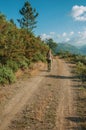 People hiking on dirt road through hilly landscape