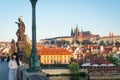 People and historic statues at sunrise of famous Charles Bridge against backdrop of city architecture