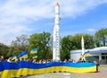 People hold large flags of Ukraine against rockets in city Dnipro - space center of Ukraine. Patriotic people with Ukrainian flags