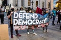 People Hold a Sign Reading `Defend Democracy` at a Progressive Rally