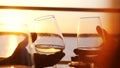 Close up of people holding glass of wine, making a toast over sunset. Friends drinking white wine Royalty Free Stock Photo