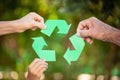 People holding recycle symbol against green spring background