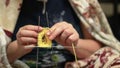 People and home concept - woman knitting by a hook and yellow yarn