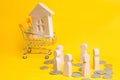 People, house in Supermarket trolley. Auction, public sales, investment attraction. Concept of real estate. Buying, selling and re Royalty Free Stock Photo