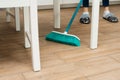 people, housework, cleaning and housekeeping concept - close up of woman legs with broom sweeping floor at home Royalty Free Stock Photo