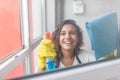 People, housework and housekeeping concept - happy woman in gloves cleaning window with rag and cleanser spray at home Royalty Free Stock Photo