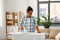 African american woman ironing bed linen at home