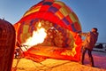 People inflate a huge balloon with a basket with a gas burner