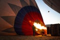 People inflating with burner flame the hot air balloon on the ground