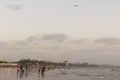 People in Juhu beach enjoying the sunset and seeing an aeroplane flying in the horizon