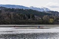 People kayaking in the distance on a lake in Bulgaria. Dark cloudy gloomy day in winter.Snowy mountains in the distance. Royalty Free Stock Photo