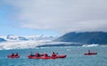People kayaking in Jokulsarlon, glacial lagoon with icebergs surrounded by mountain range, Iceland Royalty Free Stock Photo