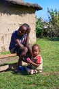 People of Kenya. Maasai children sitting on a bench near traditional adobe house