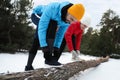 People lacing sneakers on log in winter forest. Outdoors sports exercises