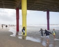 People lean into the wind under scheveningen pier on north sea beach in holland Royalty Free Stock Photo