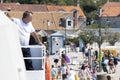 People leaving the pier, and a man working on a Jadrolinija ferry watching from the deck, on island Zlarin, Croatia