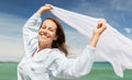 Happy woman with shawl waving in wind on beach