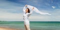 Happy woman with shawl waving in wind on beach