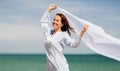 Happy woman with shawl waving in wind on beach