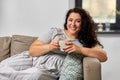 Happy woman drinking coffee or tea on sofa at home Royalty Free Stock Photo