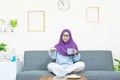 People and leisure concept,Young beautiful asian muslim woman in traditional dress wearing glasses sitting and watching TV,eating Royalty Free Stock Photo