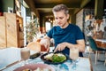 People, leisure and food concept. Young Caucasian man eating some healthy delicious meal with fork and knife at Royalty Free Stock Photo