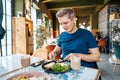 People, leisure and food concept. Young Caucasian man eating some healthy delicious meal with fork and knife at Royalty Free Stock Photo