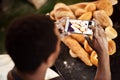 People like to see what youre up to. a male baker taking a picture on his cellphone of a selection of freshly baked