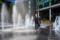 People in London, walking through between the water jets and fountains