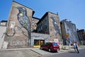 People look at the building exterior with two birds graffiti