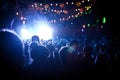 People looking at a festival stage at night with colour lighting