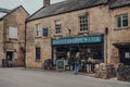 People looking at products on a window display of Bakery on the Water shop in Bourton-on-the-Water, Cotswolds, UK