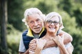 People in love at old age - couple of caucasian cheerful happy senior smile and hug in relationship - green defocused forest in Royalty Free Stock Photo