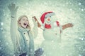 People Love winter. Snowing winter beauty fashion concept. Girl playing with snowman in winter park. Joyful Beauty young Royalty Free Stock Photo