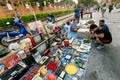 People making choice on second hand market outdoor with radio, tv-sets and other goods