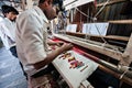 People making colorful silk yarn fabric by Indian weaving loom