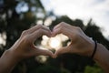 People are making a heart-shaped hand, with a beautiful background, a bokeh of sunlight and a tree in the concept of love Royalty Free Stock Photo
