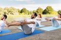 People making yoga in half-boat pose outdoors