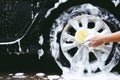 people man holding hand yellow sponge for washing car. cleaning wheel tire. Royalty Free Stock Photo