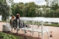 2 people, man and woman sitting on a Park bench on the Bank of a pond, a couple